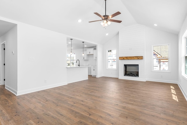 unfurnished living room with ceiling fan, a fireplace, and dark wood-type flooring