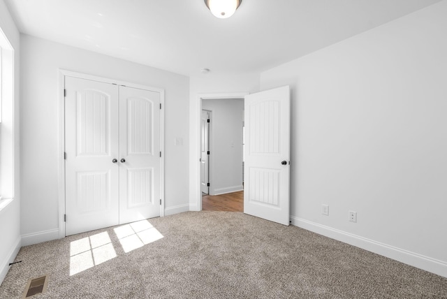 unfurnished bedroom with light carpet and a closet