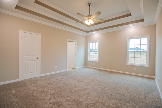 spare room featuring a tray ceiling, ceiling fan, light carpet, and ornamental molding