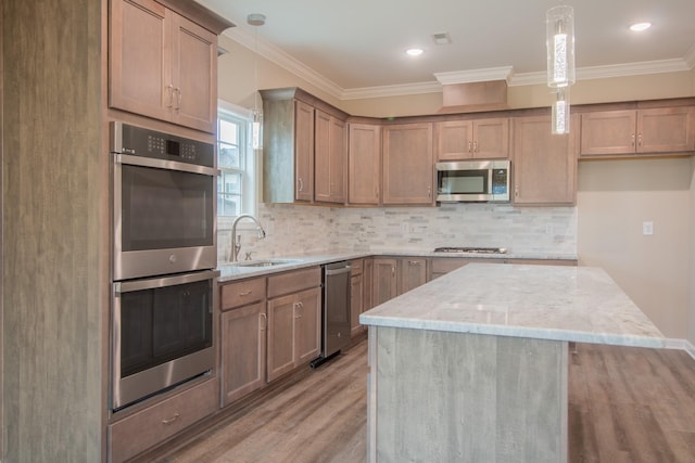 kitchen featuring a center island, sink, light stone countertops, appliances with stainless steel finishes, and light hardwood / wood-style floors