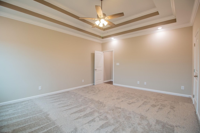 empty room featuring light colored carpet, a raised ceiling, ceiling fan, and ornamental molding