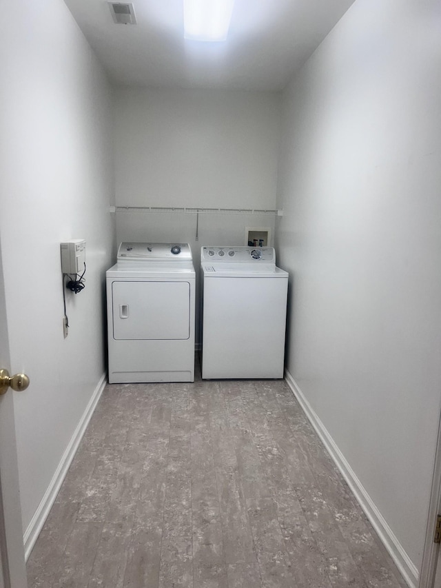 washroom featuring washing machine and clothes dryer and light hardwood / wood-style flooring