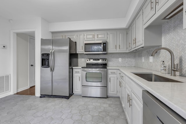 kitchen featuring decorative backsplash, light tile patterned flooring, sink, and stainless steel appliances