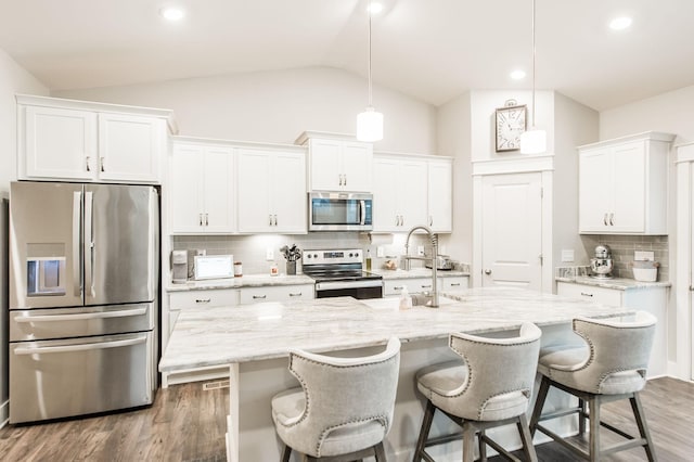 kitchen featuring tasteful backsplash, stainless steel appliances, pendant lighting, white cabinets, and lofted ceiling