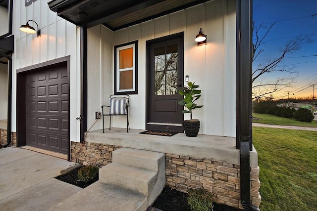 exterior entry at dusk with a garage, covered porch, and a yard