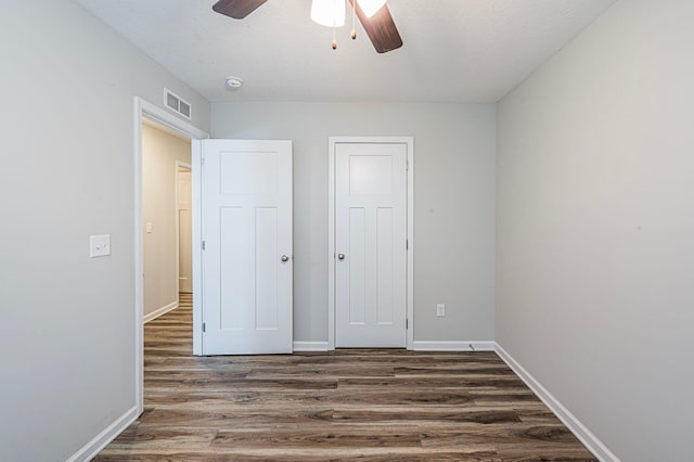 unfurnished bedroom with ceiling fan, dark hardwood / wood-style flooring, and a closet