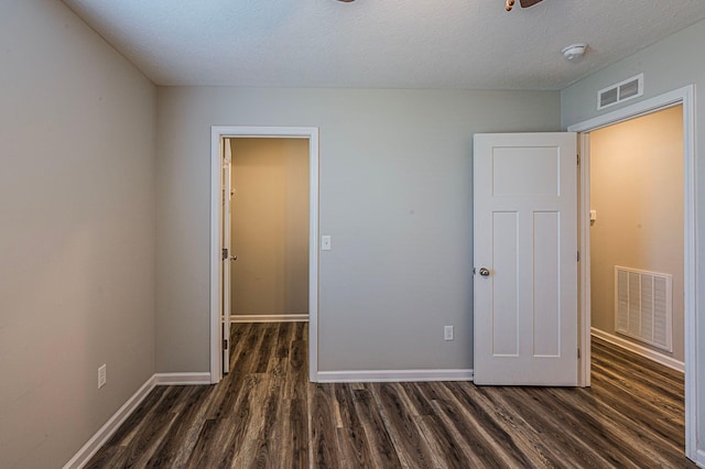 unfurnished bedroom featuring a textured ceiling and dark hardwood / wood-style floors