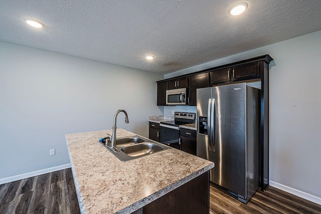 kitchen featuring dark hardwood / wood-style flooring, sink, stainless steel appliances, and a kitchen island with sink