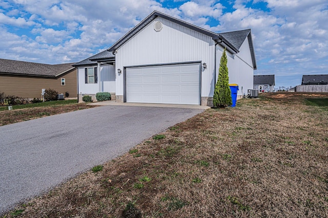 view of front of house with central air condition unit, a front lawn, and a garage