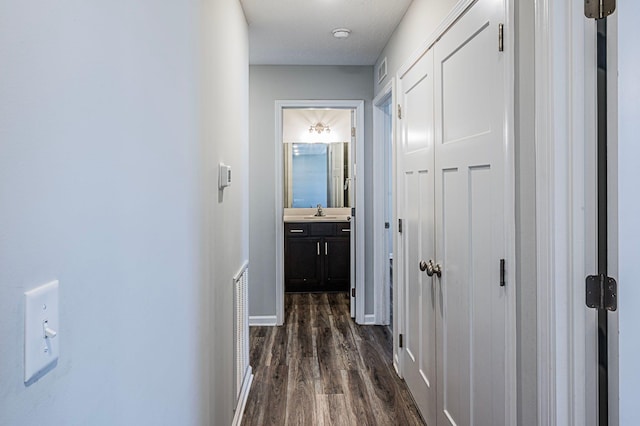 corridor with dark hardwood / wood-style flooring and sink