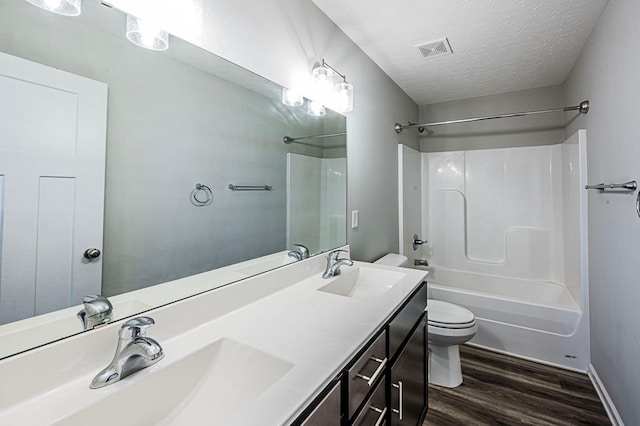 full bathroom with shower / bathing tub combination, a textured ceiling, toilet, vanity, and hardwood / wood-style flooring