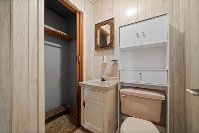 bathroom featuring vanity, toilet, and wooden walls