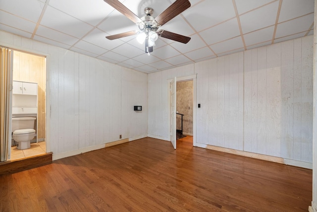 spare room with a paneled ceiling, hardwood / wood-style flooring, and wooden walls