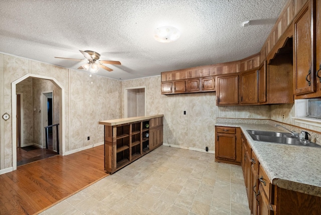 kitchen with a textured ceiling, light wood-type flooring, and sink