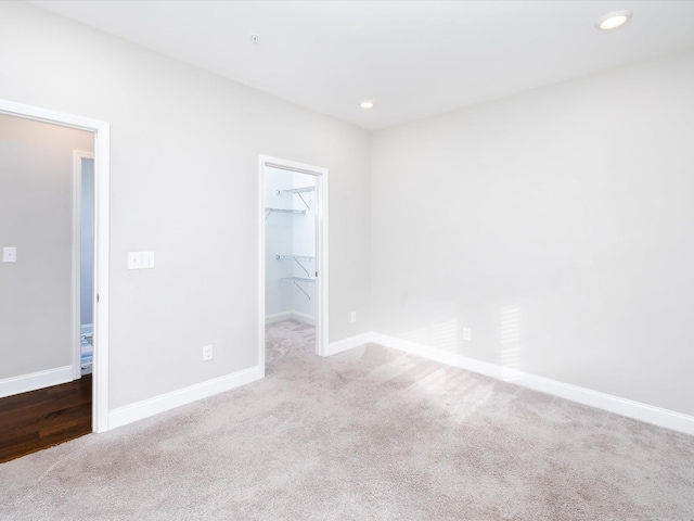 unfurnished bedroom with a walk in closet, light carpet, and a closet