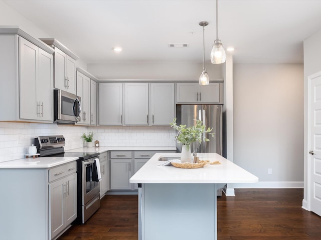 kitchen with a center island, gray cabinets, dark wood-type flooring, and appliances with stainless steel finishes