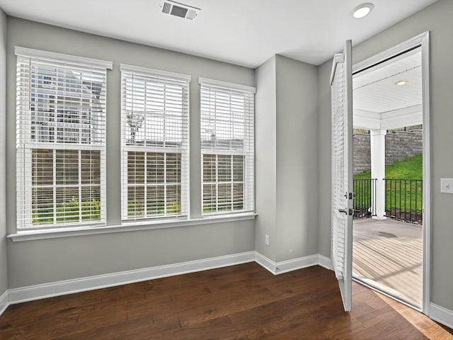 spare room featuring dark hardwood / wood-style flooring and a healthy amount of sunlight