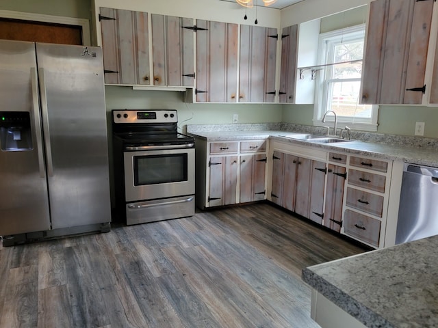 kitchen with appliances with stainless steel finishes, dark hardwood / wood-style flooring, and sink