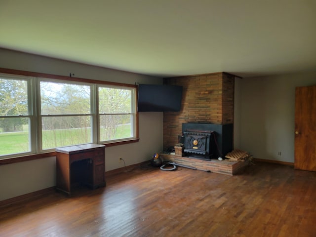 unfurnished living room with wood finished floors, baseboards, and a wood stove