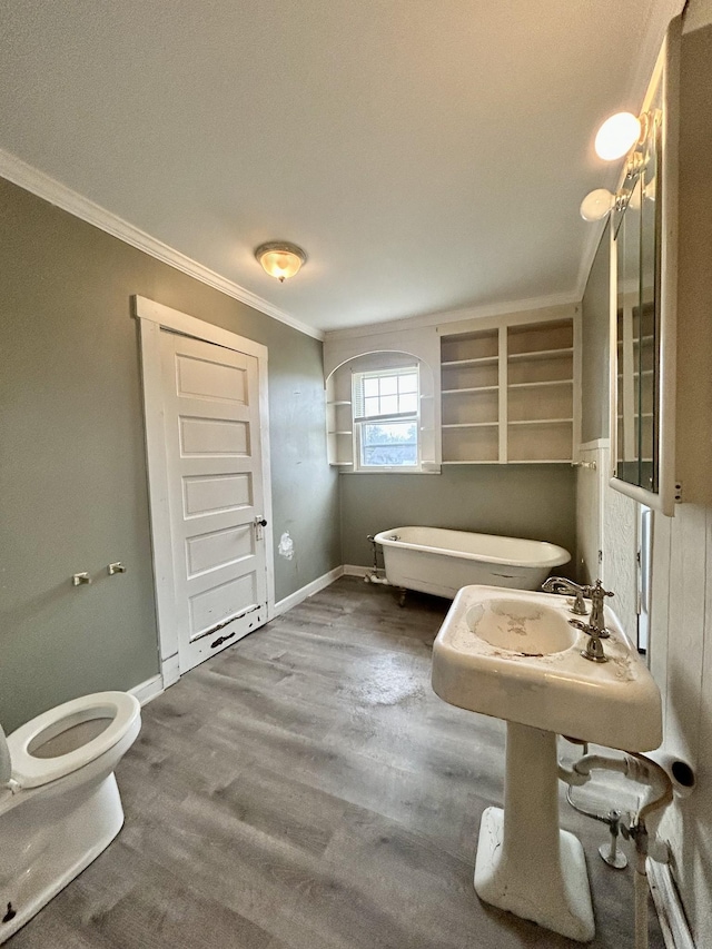 bathroom with a bathing tub, hardwood / wood-style floors, toilet, and ornamental molding