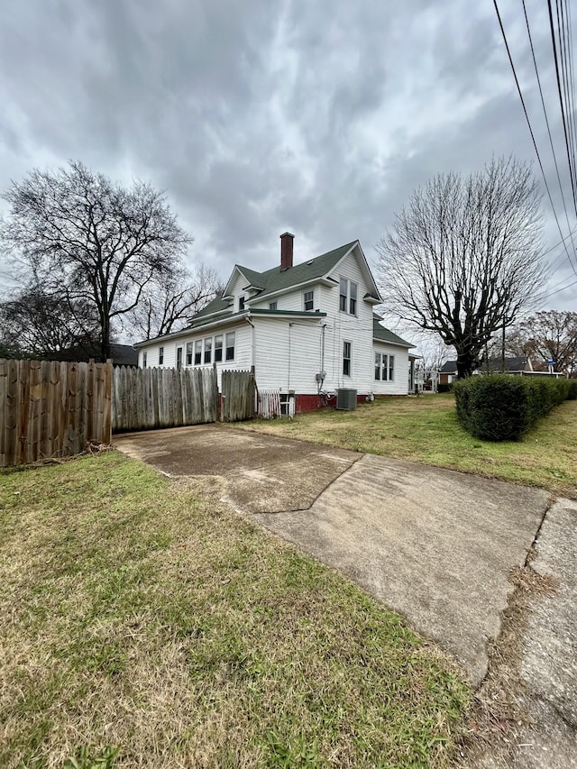 view of side of home with a yard and central air condition unit