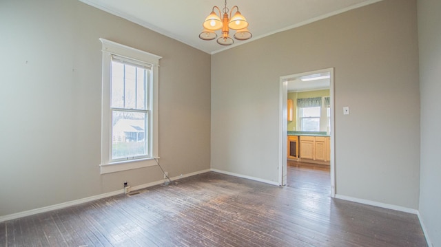 empty room featuring a chandelier, dark wood-type flooring, a healthy amount of sunlight, and ornamental molding