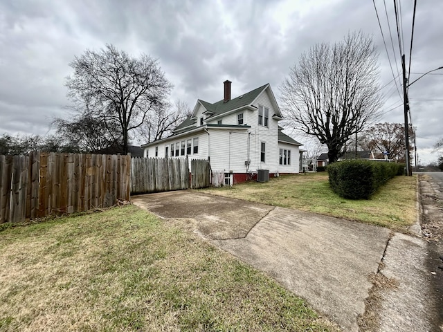 view of side of home featuring a lawn and central AC unit