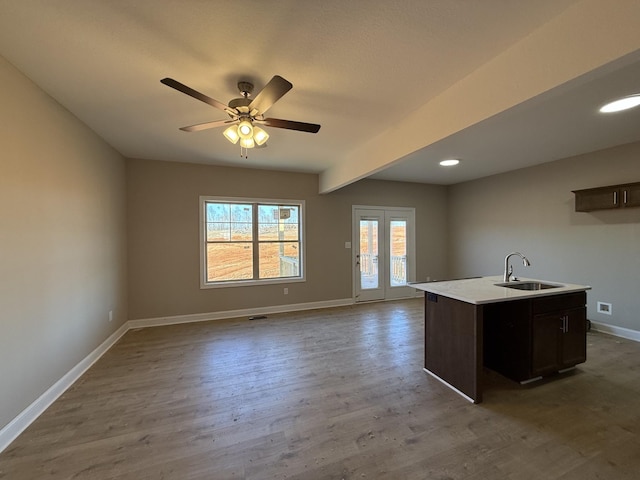 kitchen featuring open floor plan, wood finished floors, a sink, and baseboards