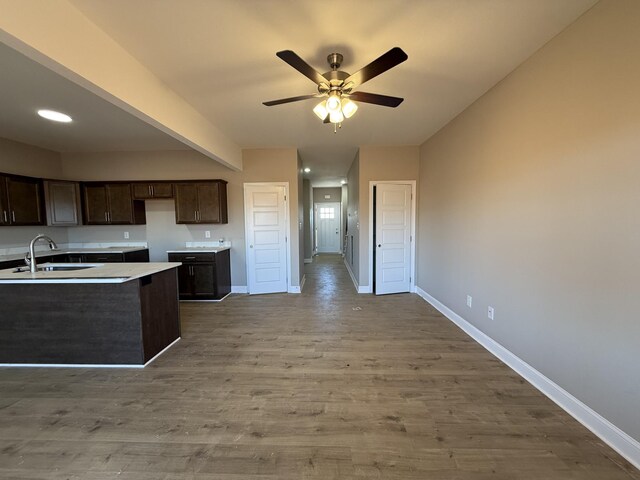 kitchen featuring dark brown cabinetry, baseboards, a sink, and wood finished floors