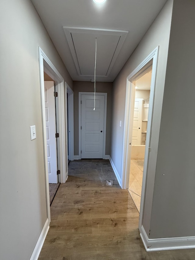 hallway with attic access, baseboards, and wood finished floors