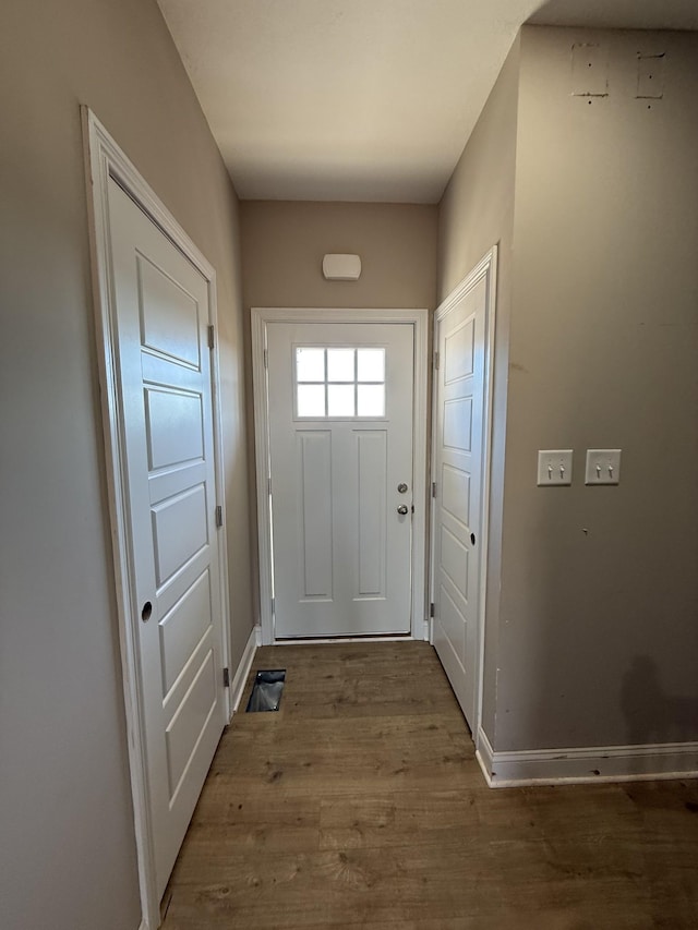 doorway with wood finished floors and baseboards