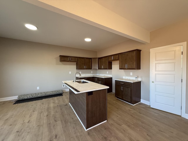 kitchen with baseboards, dark brown cabinets, a sink, and wood finished floors