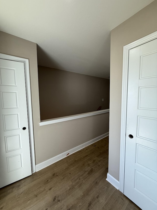 corridor with wood finished floors and baseboards