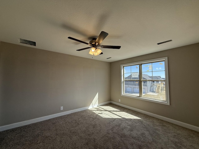 carpeted spare room with a ceiling fan, visible vents, and baseboards