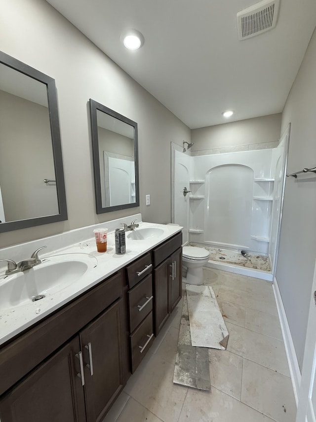 bathroom with toilet, visible vents, a walk in shower, and a sink