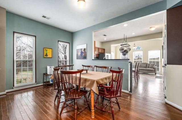 dining area featuring wood-type flooring, a textured ceiling, and a notable chandelier