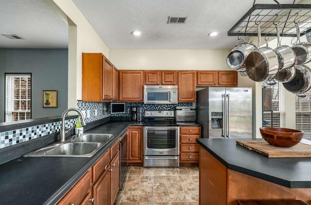 kitchen with tasteful backsplash, sink, a textured ceiling, and appliances with stainless steel finishes