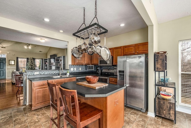 kitchen featuring ceiling fan, sink, kitchen peninsula, a kitchen island, and appliances with stainless steel finishes