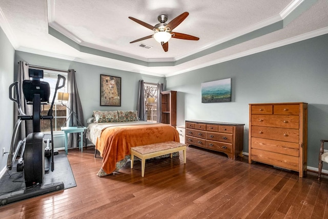 bedroom with ceiling fan, wood-type flooring, ornamental molding, and a tray ceiling