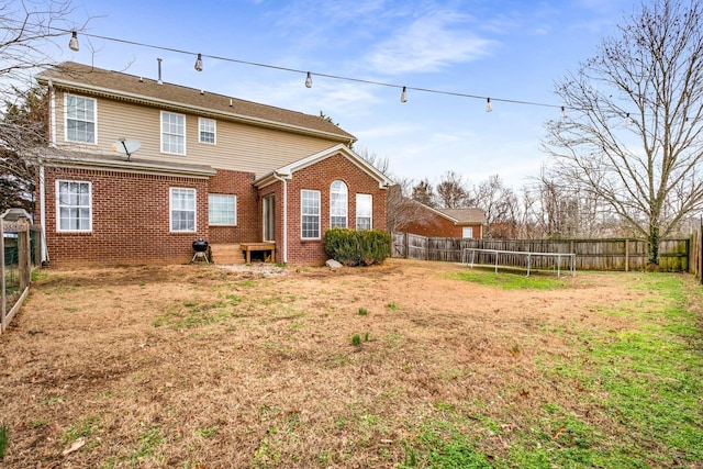 back of property featuring a trampoline and a lawn