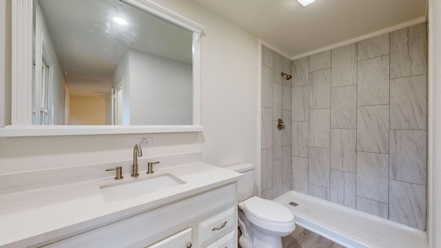 bathroom with a tile shower, vanity, toilet, and wood-type flooring