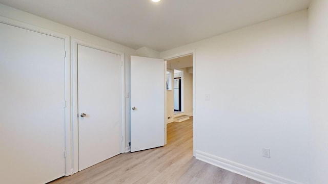 unfurnished bedroom featuring white fridge and light hardwood / wood-style flooring