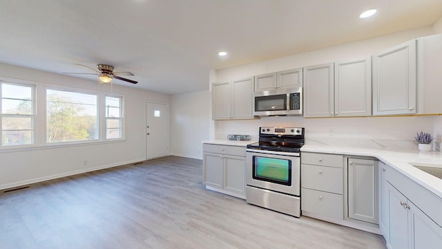 kitchen with appliances with stainless steel finishes, light hardwood / wood-style floors, and ceiling fan