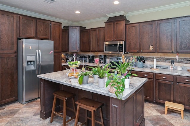 kitchen with dark brown cabinets, a center island, ornamental molding, and appliances with stainless steel finishes