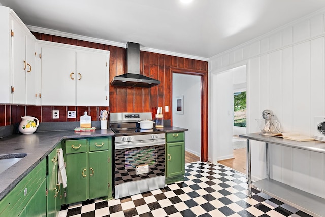 kitchen featuring stainless steel range, wall chimney exhaust hood, wood walls, white cabinets, and ornamental molding