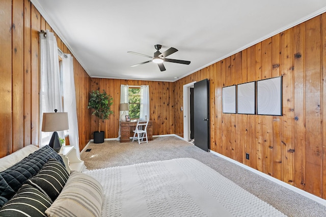 bedroom with carpet, ceiling fan, wood walls, and ornamental molding