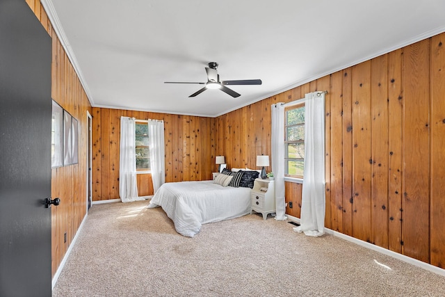 carpeted bedroom with wooden walls, ceiling fan, and ornamental molding