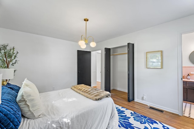 bedroom with a chandelier, hardwood / wood-style floors, and ensuite bathroom