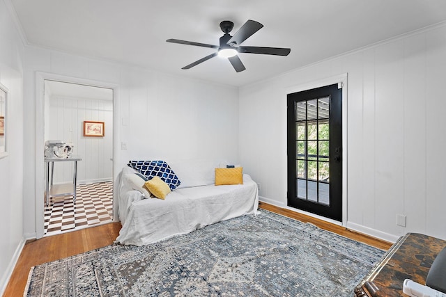 living area featuring wood-type flooring, ceiling fan, and crown molding