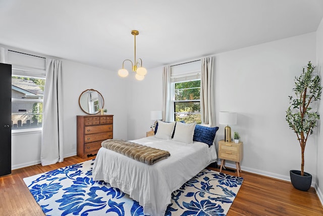 bedroom with hardwood / wood-style floors, an inviting chandelier, and multiple windows